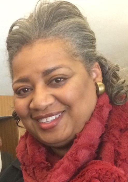 Smiling woman with gold earrings and a cozy red scarf.