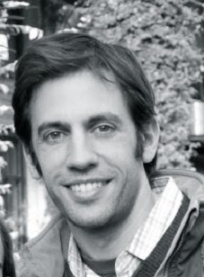 Black and white photo of a man with short hair, smiling at the camera.