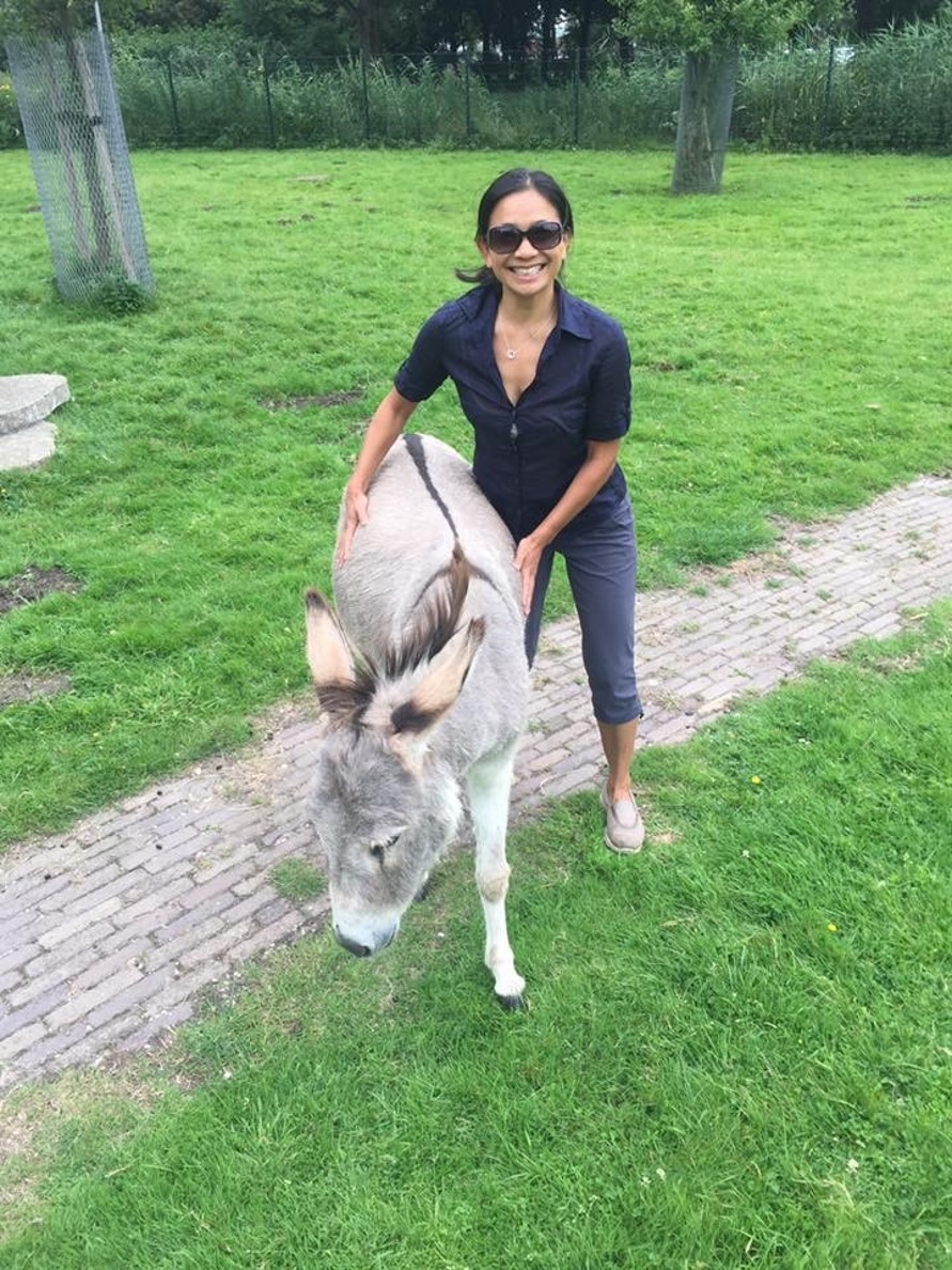 A woman posing with a donkey, smiling.
