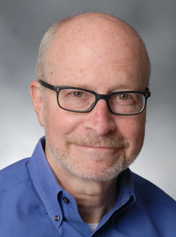 Man with black frame glasses and silver stubble