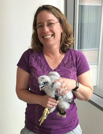 A woman smiling, holding a baby bird.