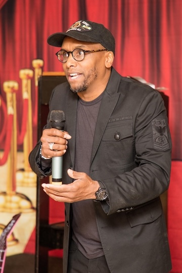 Andre speaking at an event, holding a microphone
